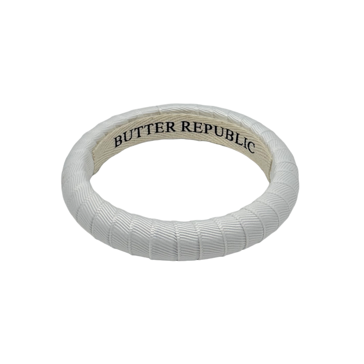 white narrow Butter Republic bracelet with logo brand label visible on the interior of the bracelet