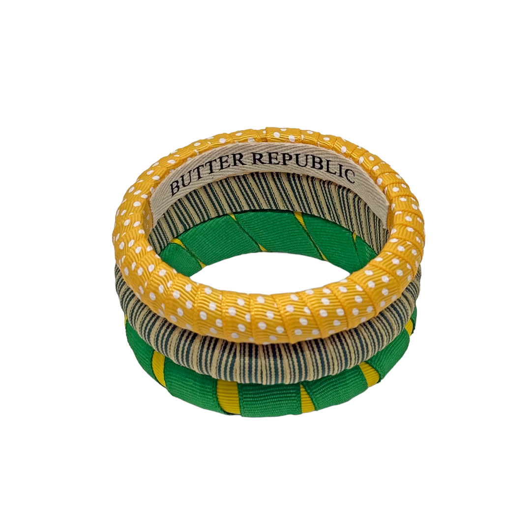 Stack of green and yellow Butter Republic bangles with brand label on the interior