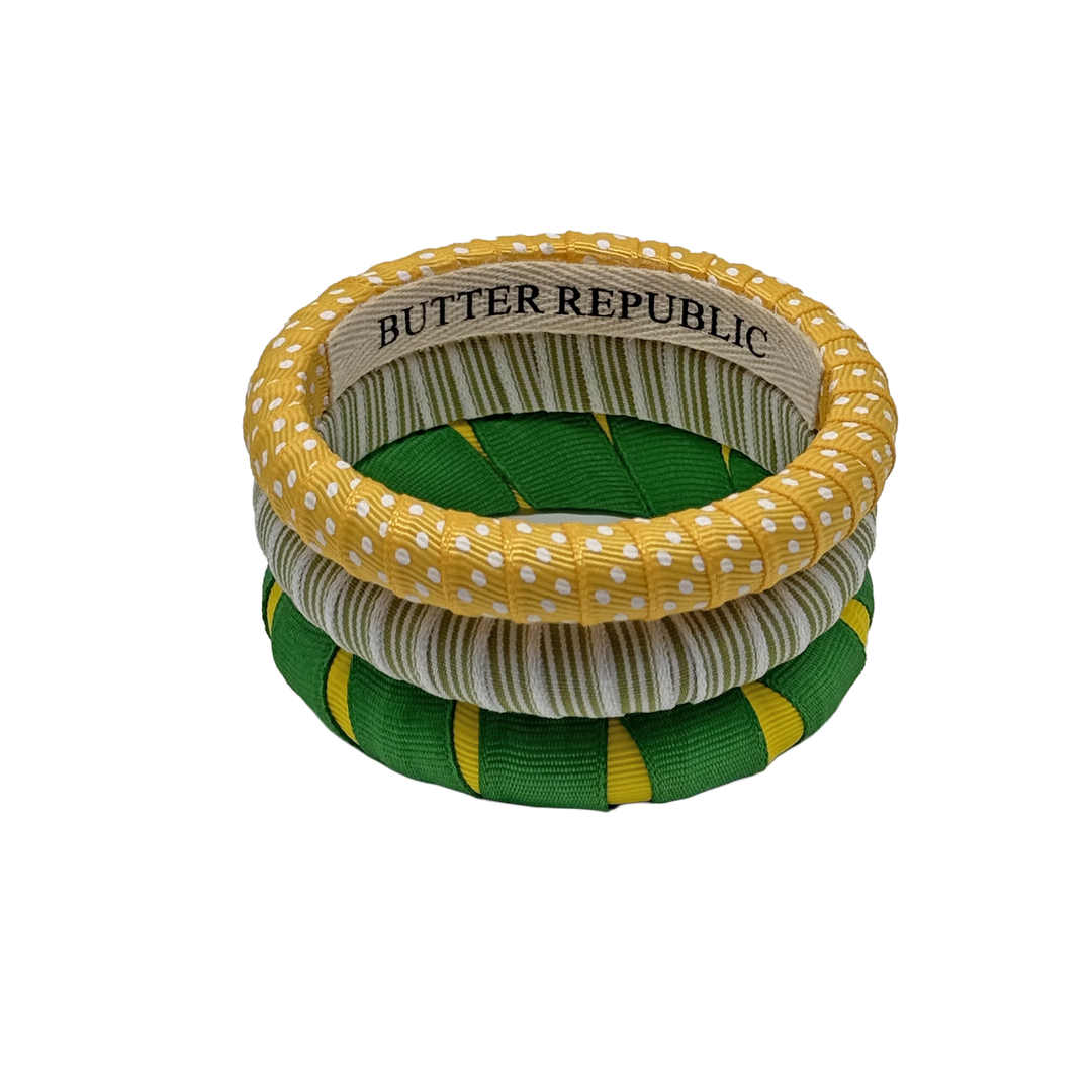 three multi-sized green and yellow Butter Republic bracelets with logo brand label visible on the interior of one of the bracelets
