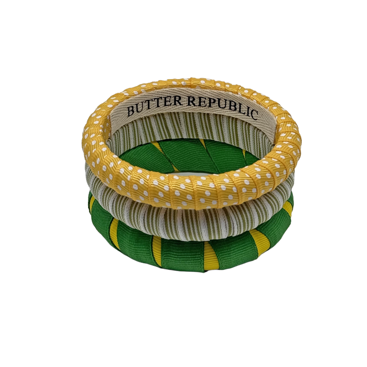 three multi-sized green and yellow Butter Republic bracelets with logo brand label visible on the interior of one of the bracelets