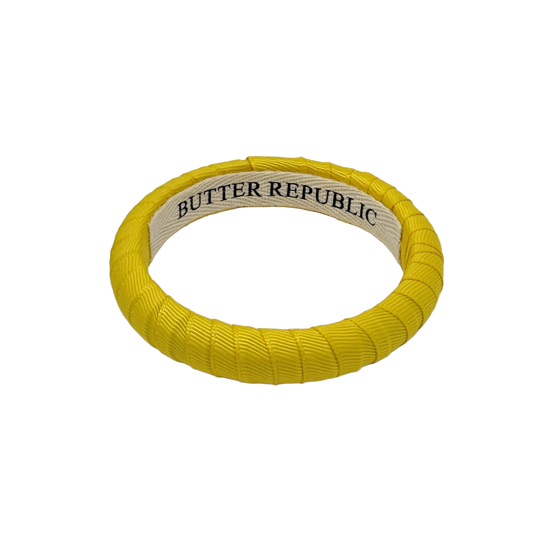 yellow narrow Butter Republic bracelet with logo brand label visible on the interior of the bracelet