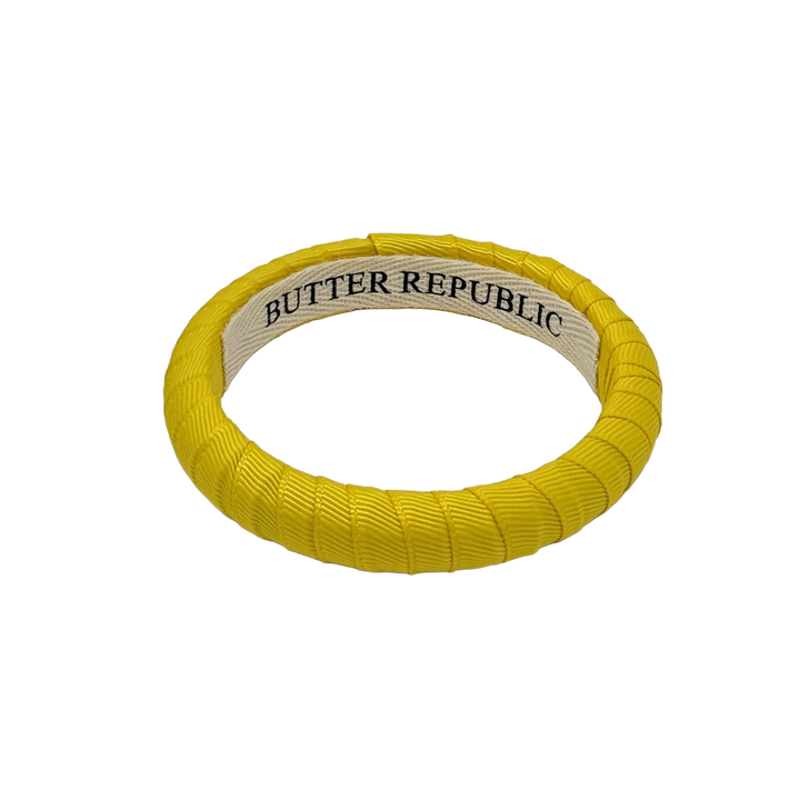 yellow narrow Butter Republic bracelet with logo brand label visible on the interior of the bracelet