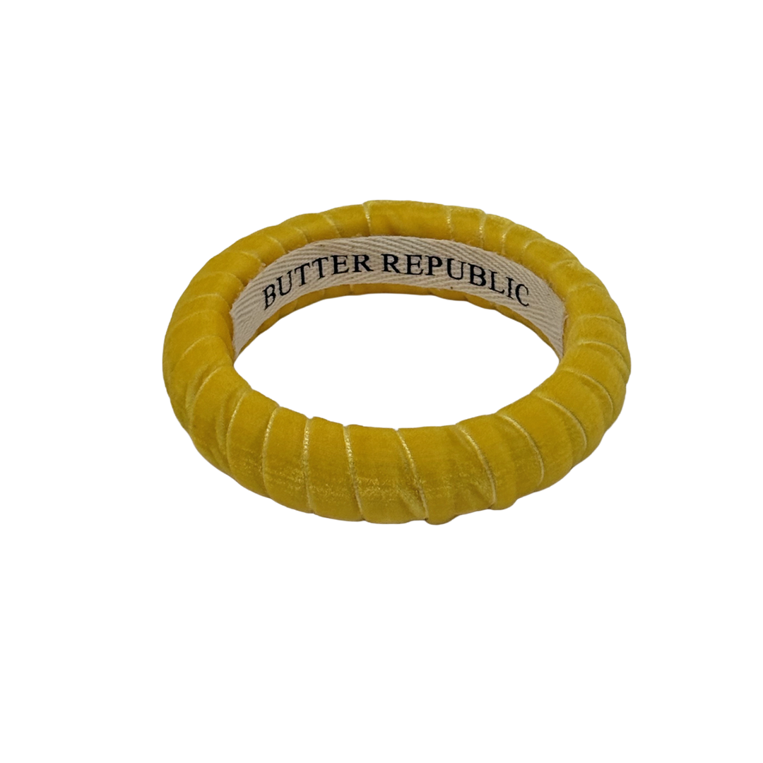 yellow velvet Butter Republic bracelet with logo brand label visible on the interior of the bracelet