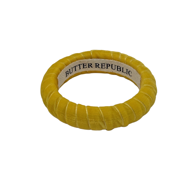 yellow velvet Butter Republic bracelet with logo brand label visible on the interior of the bracelet