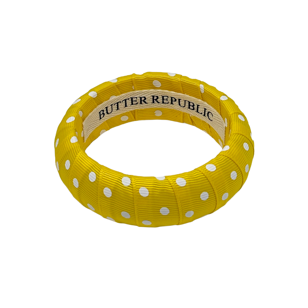 Yellow and white polka dot bangle bracelet with Butter Republic brand label on the interior