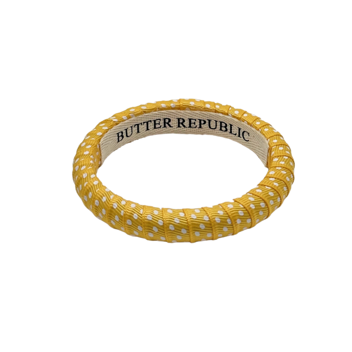 yellow and white Swiss dots Butter Republic bracelet with logo brand label visible on the interior of the bracelet